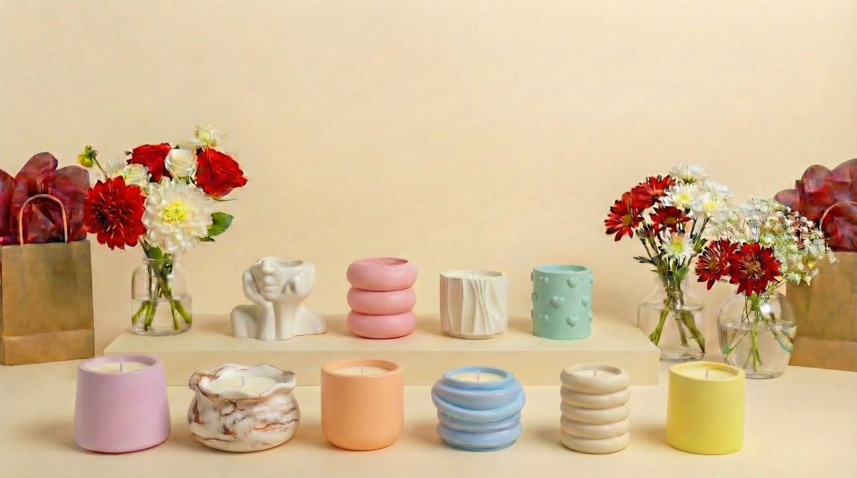 Colorful containers and candles on a beige surface with flowers in the background