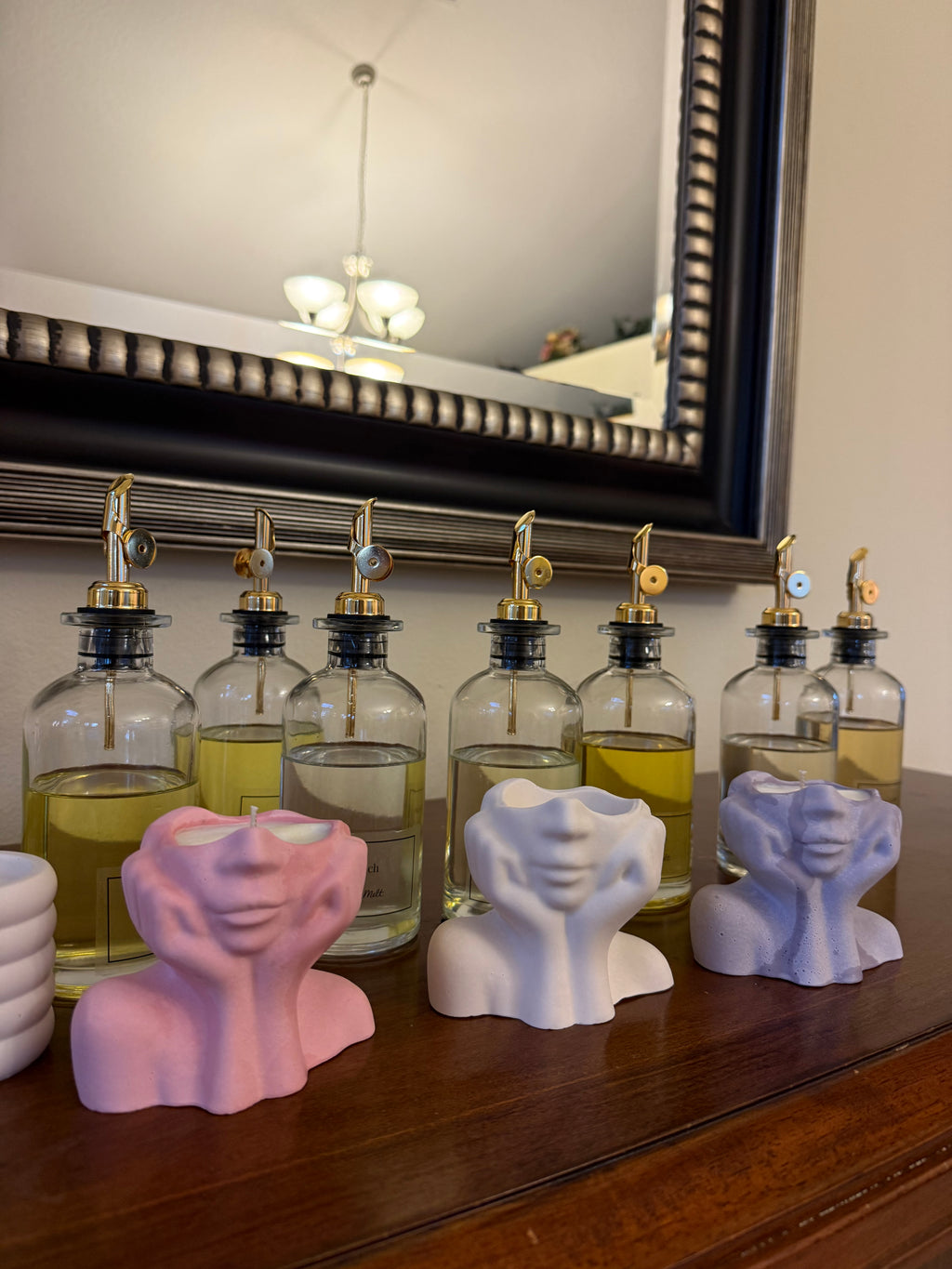 Three Muse candle vessels in pink, white, and lavender lined up beside fragrance oil bottles at a Set & Melt workshop in Orlando