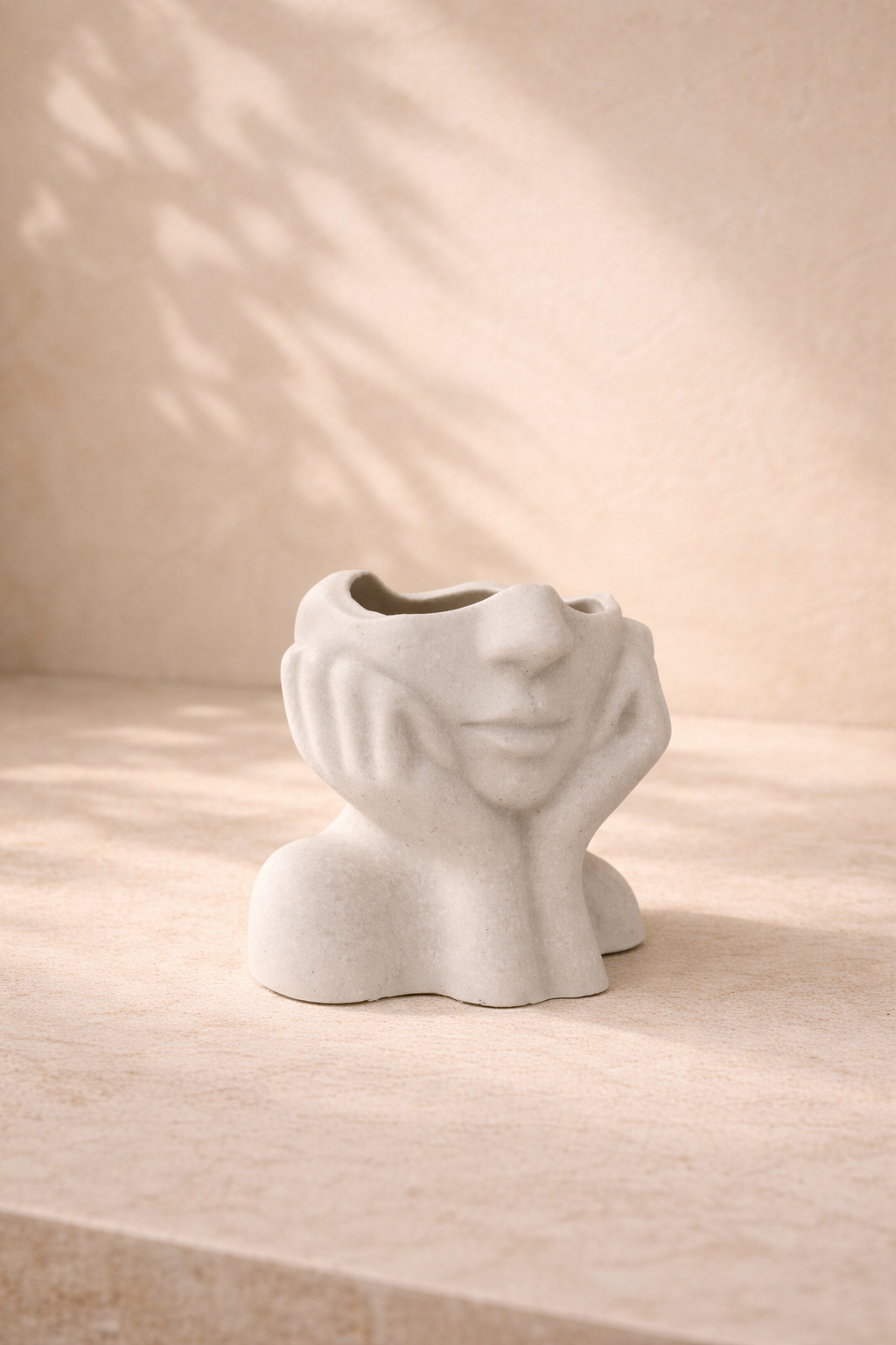 Matte sculptural face-shaped candle vessel in mineral composite with artistic facial details on neutral background.