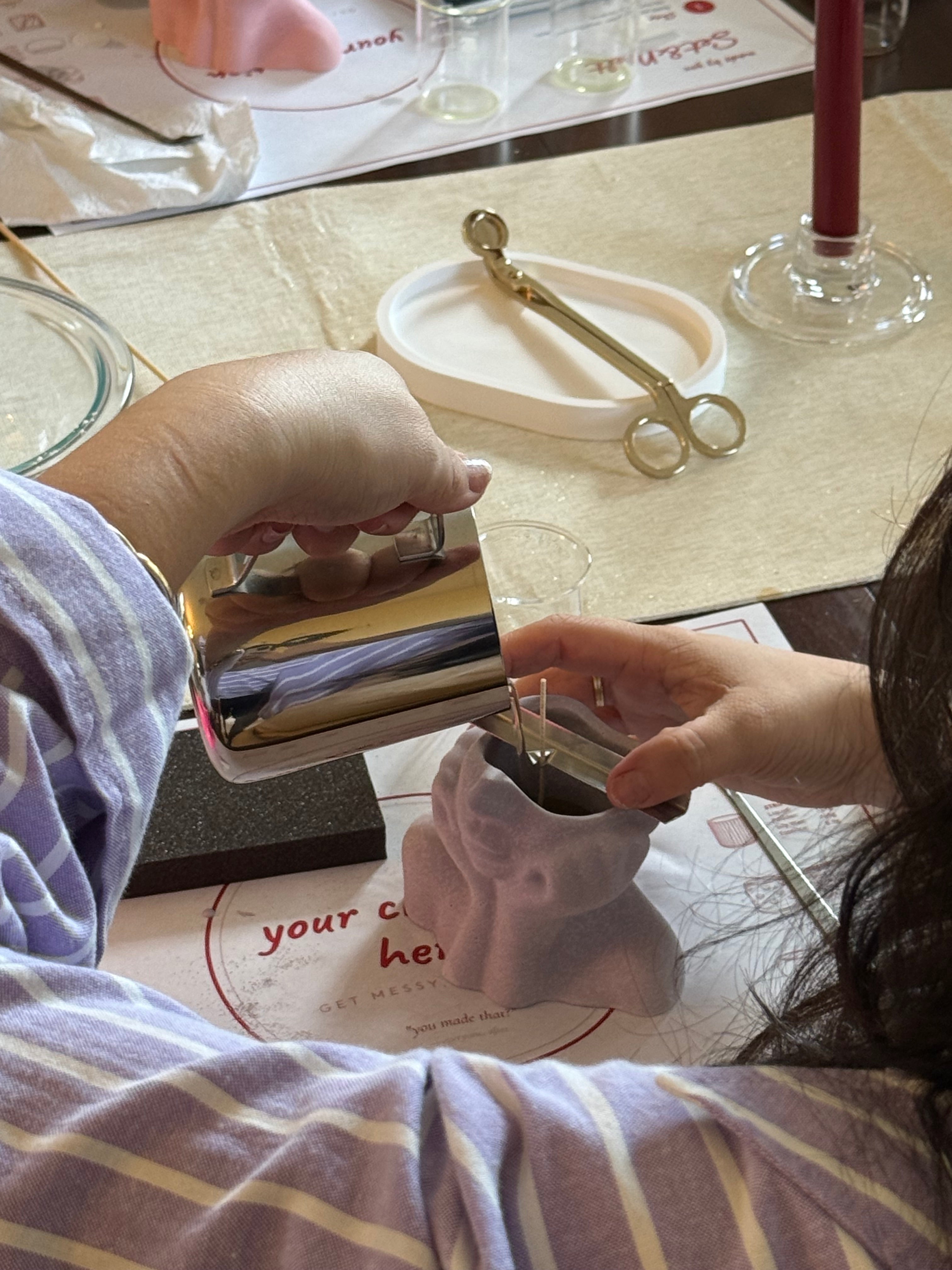 Guest pouring melted soy wax into a handmade candle vessel during a Set & Melt candle making workshop.